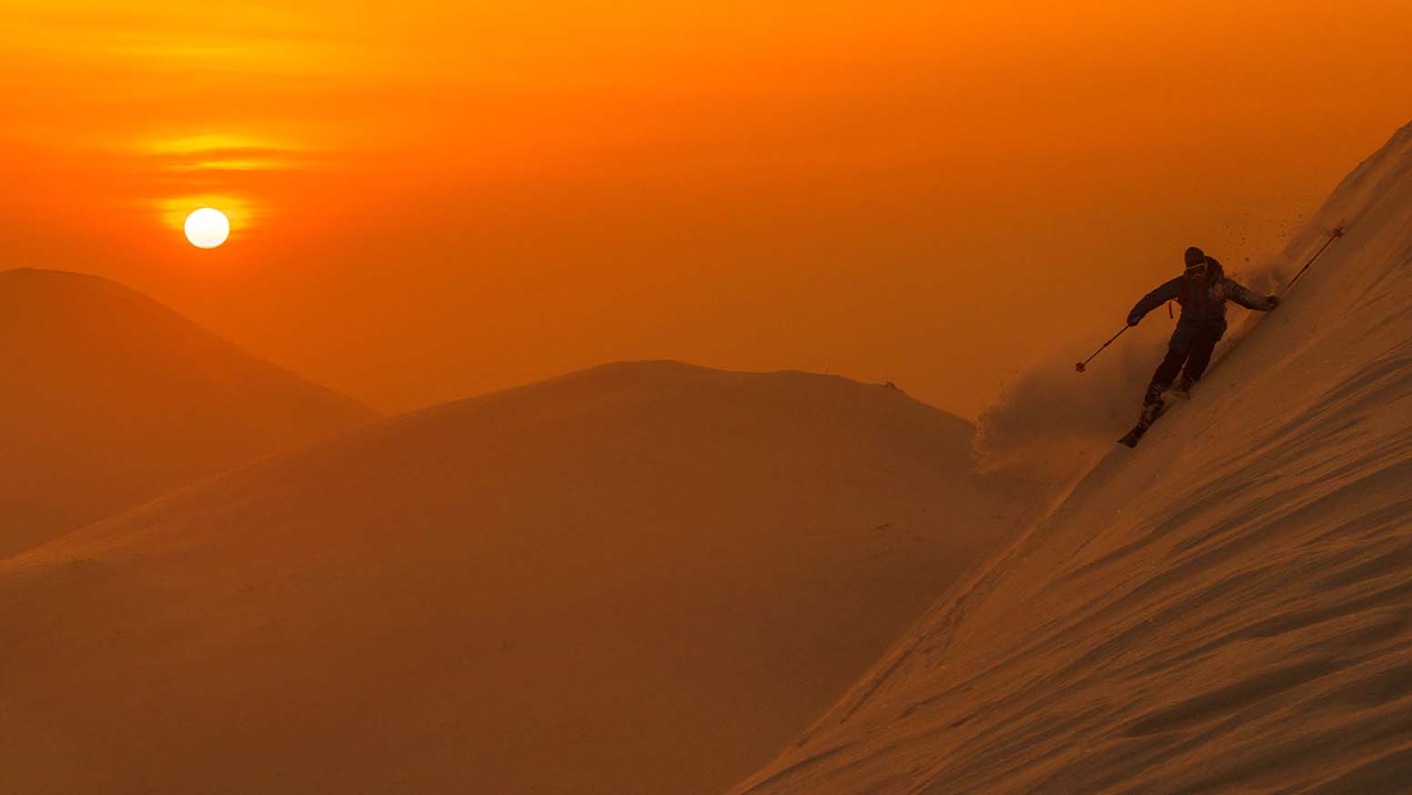 A person skiing in the snow during sunrise