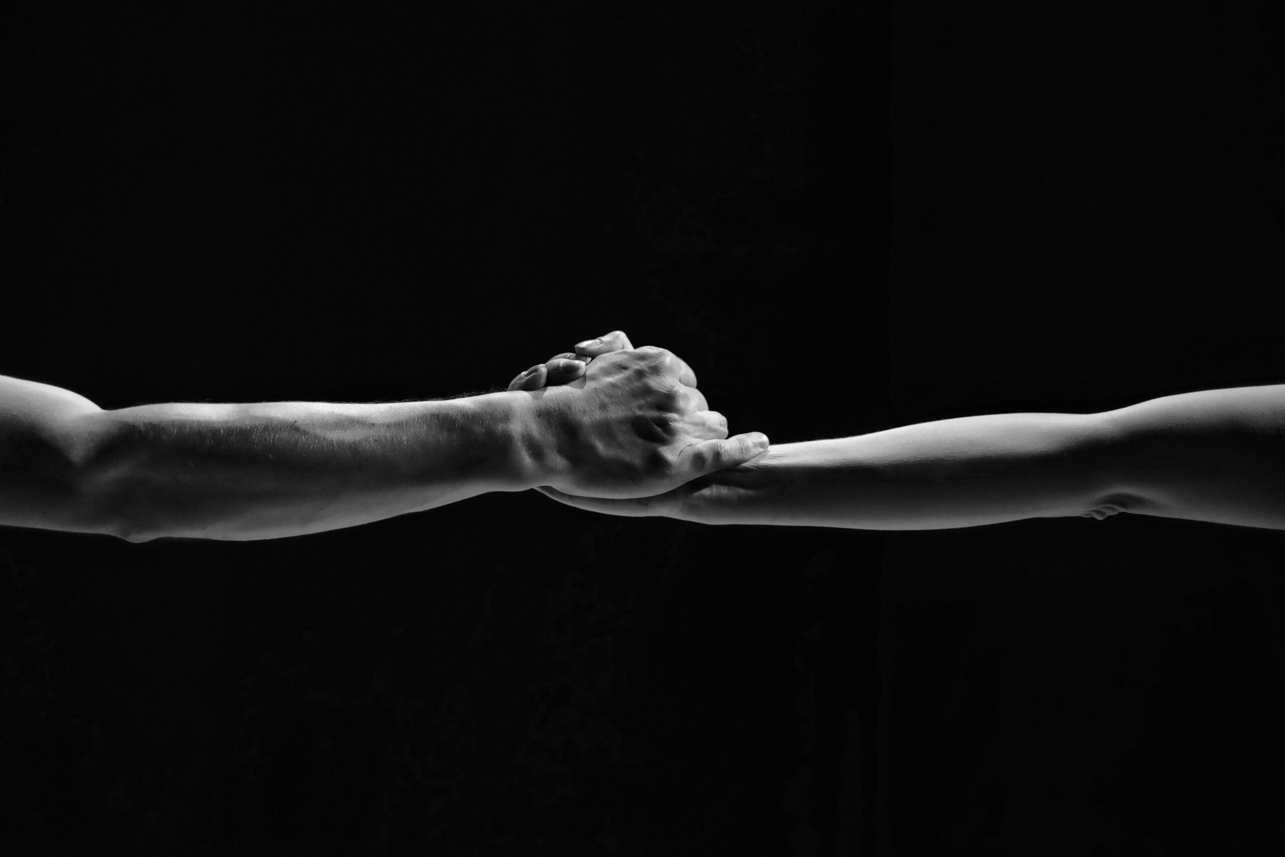 Couple holding hands in the dance. Male and female hands close-up on a black background.