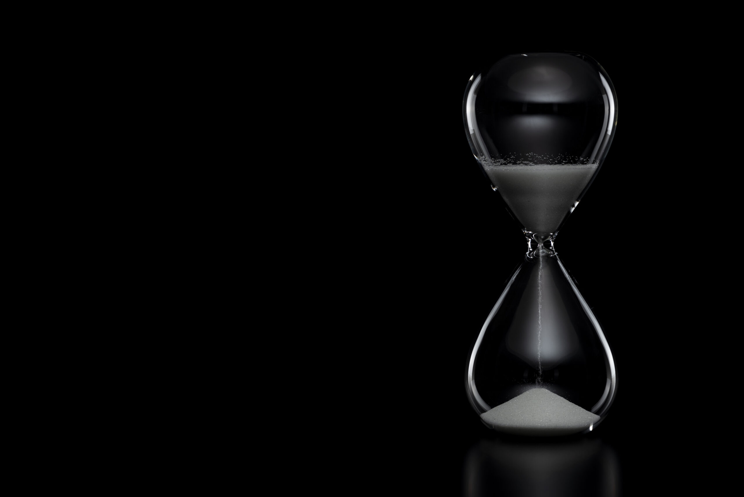 Close up of hourglass on black background.