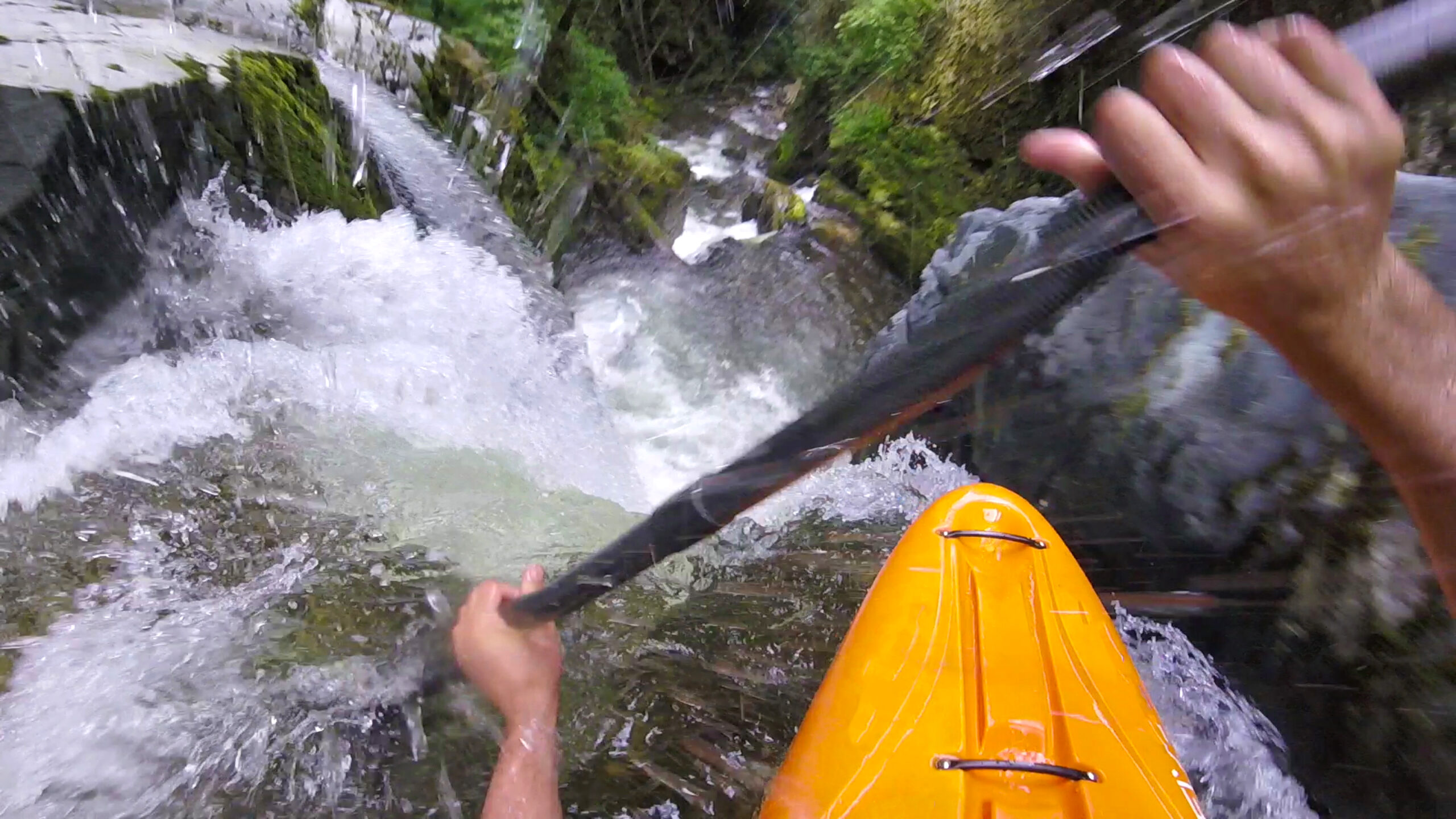 White water kayaker paddles down waterfall