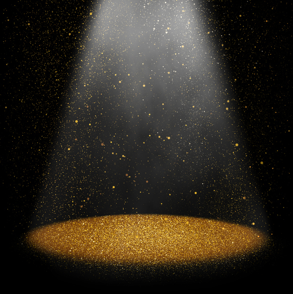 Twinkling gold glitter falling on the stage illuminated with one spot light