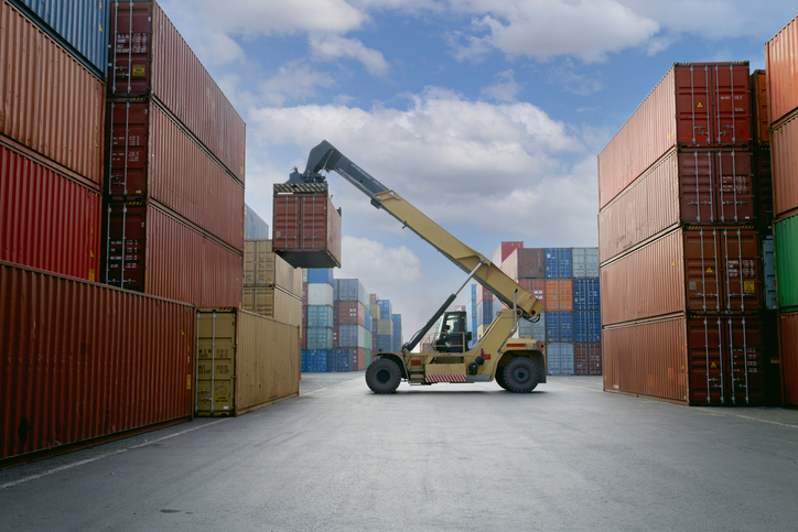 Forklift lifting up container in commercial port.