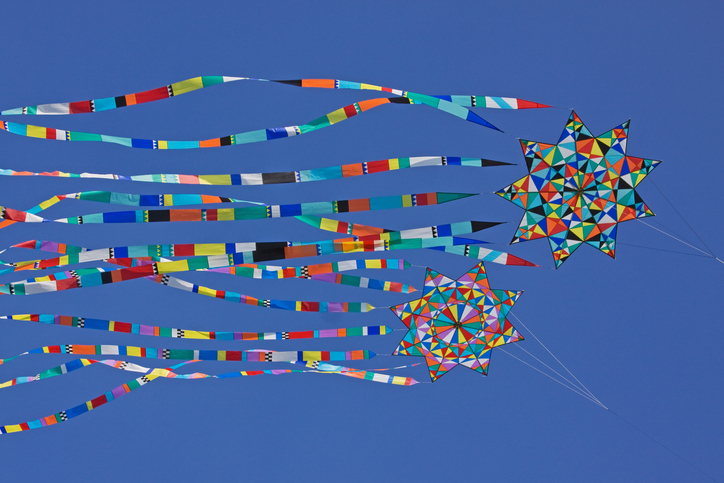 Multi colored kites flying against a blue sky