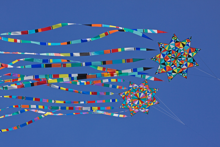 Multi colored kites flying against a blue sky